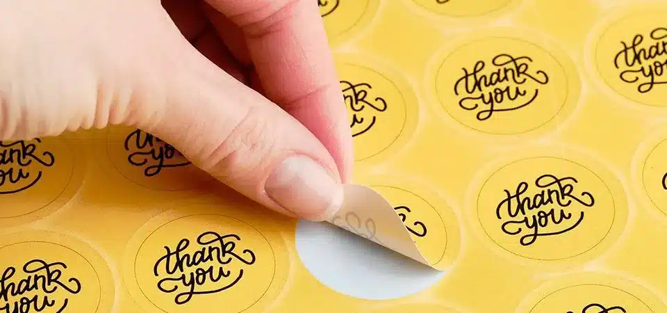 Small Business Using Logo Stickers A small business owner happily placing a logo sticker on a kraft paper bag at a market stall
