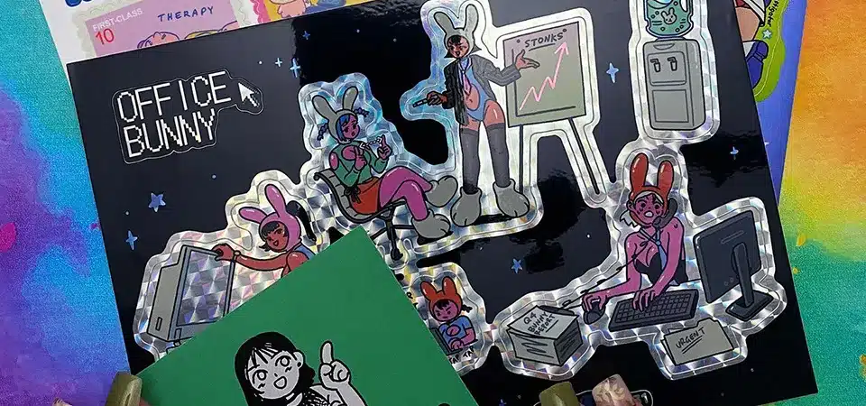 An overhead shot of a designer arranging multiple different sticker graphics onto a single A4-sized digital template