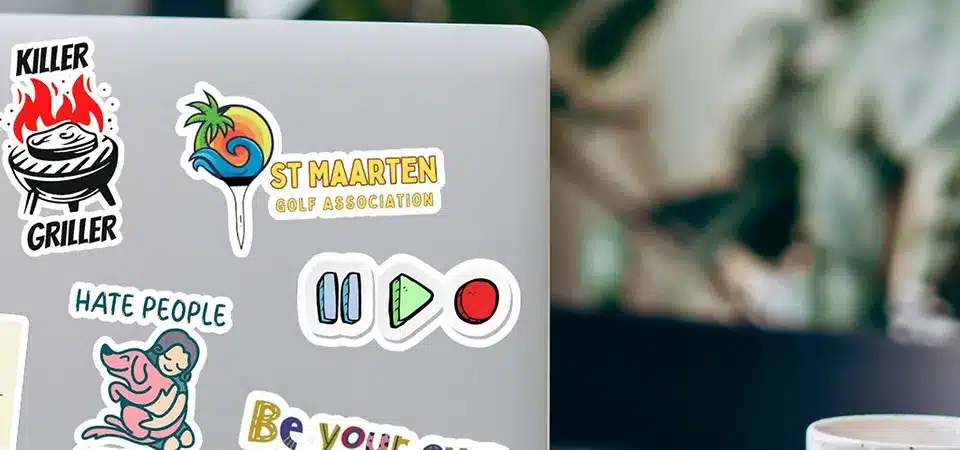 A customer's hand holding a sample pack of different sticker materials from a supplier