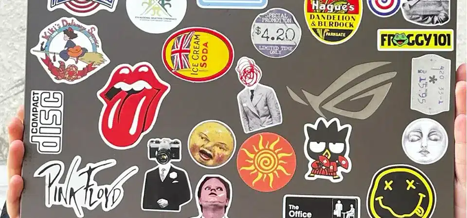 A person's laptop covered in various cool stickers, including one from a small coffee shop