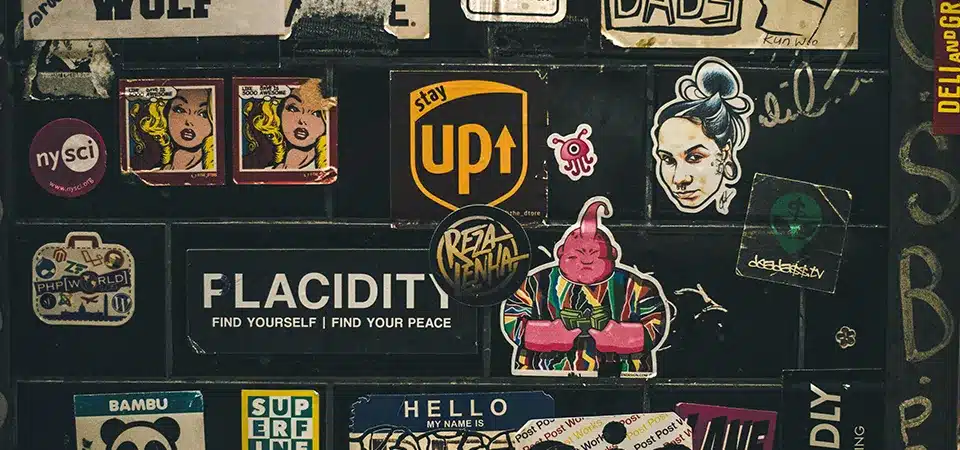 A person proudly showing off a laptop covered in cool, well-designed brand stickers